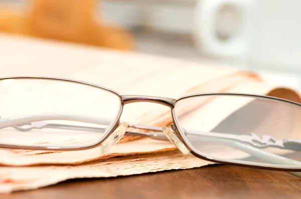 Eyeglasses on the newspaper on a wooden table — Stock Photo, Image