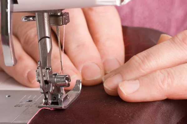 The elderly woman sews on the sewing machine — Stock Photo, Image