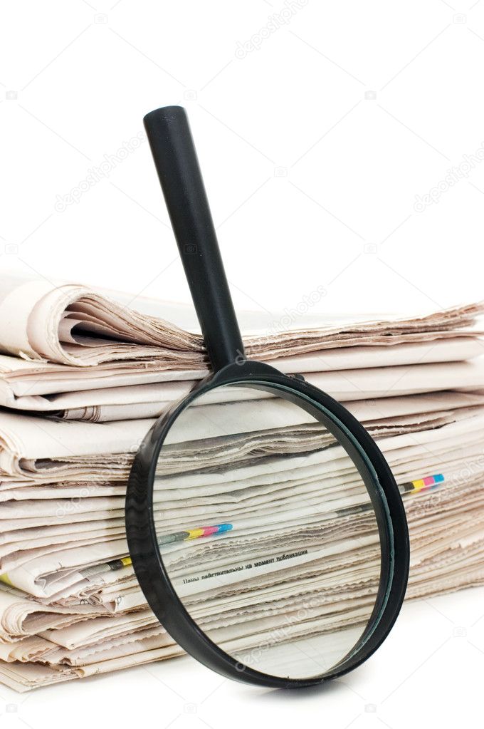 Magnify glass over a stack of newspaper