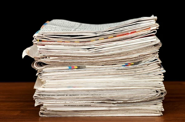 Heap of newspaper on a wooden table — Stock Photo, Image