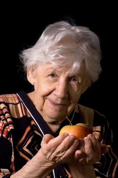 Pomme dans une main de la vieille femme sur le noir — Photo