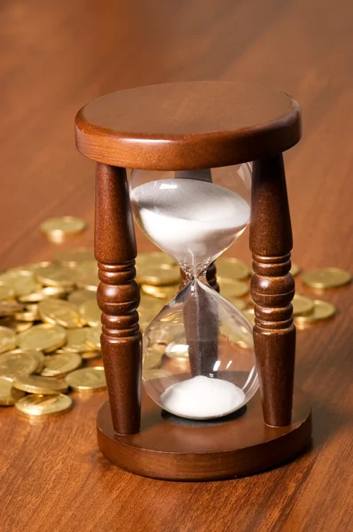 Hourglasses ve sikke üzerinde ahşap bir masa — Stok fotoğraf