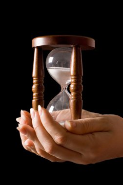 Hourglass in hands on a black background clipart