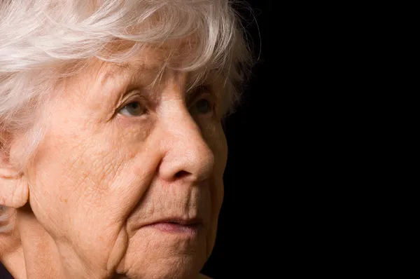 Az idős asszony egy fekete háttér portréja — Stock Fotó