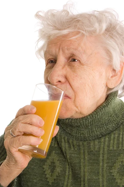 De oudere vrouw met een glas sap — Stockfoto