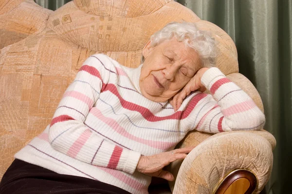 De oudere vrouw slaapt op een sofa — Stockfoto