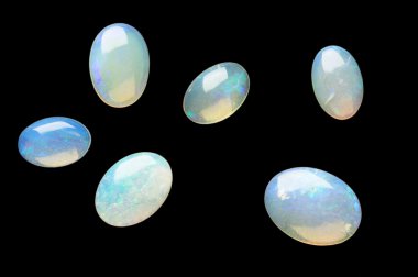 Few white opals isolated on black. clipart