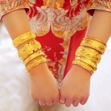 Numerous golden wedding bangles on Chinese bride's arms clipart