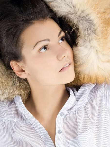 Beautiful young woman lying in a fur — Stock Photo, Image