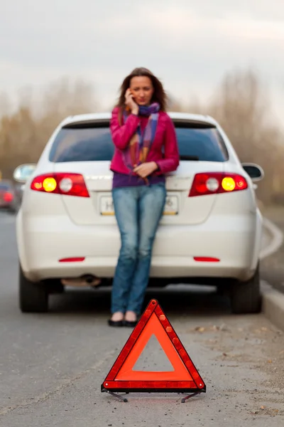 Una donna chiama ad un servizio in piedi vicino ad una macchina bianca — Foto Stock