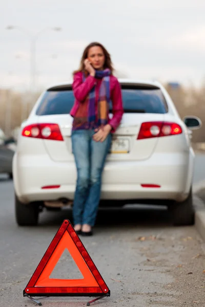 Mujer llama a un servicio de pie junto a un coche blanco — Foto de Stock