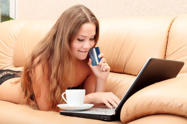 Женщина лежит на диване и делает покупки в Интернете — стоковое фото