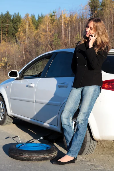 Mujer joven de pie junto a su coche dañado — Foto de Stock