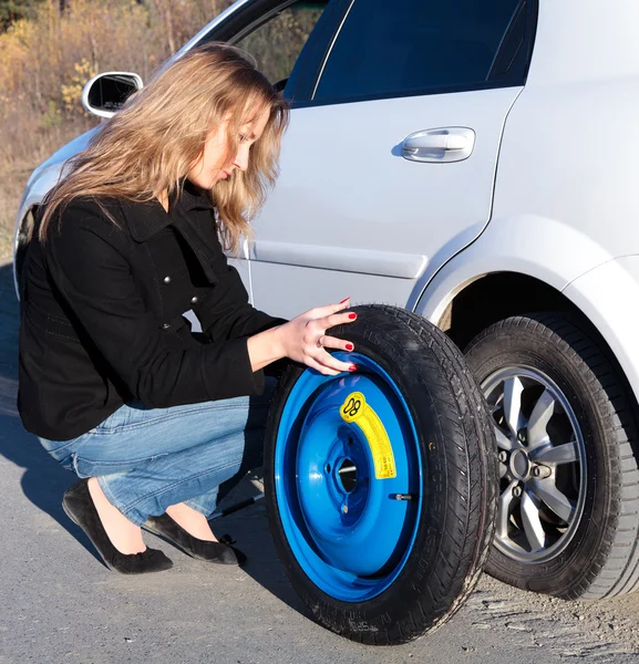 Mujer joven y el coche con la rueda desinflada — Foto de Stock