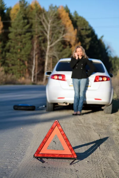 Young woman standing by her damaged car and calling for help — Stock Photo, Image