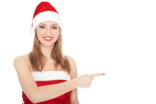 Leende kvinna i santa röd hatt pekar på tomt utrymme — Stockfoto