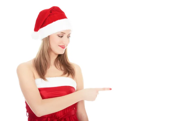 Lächelnde Frau mit Weihnachtsmann-roter Mütze zeigt auf leeren Raum. — Stockfoto