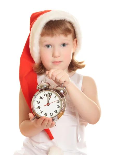 Little girl wearing red Santa's hat with a big alarm clock — Stock Photo, Image