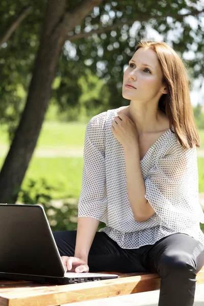 Hezká mladá žena s laptopem v parku — Stock fotografie