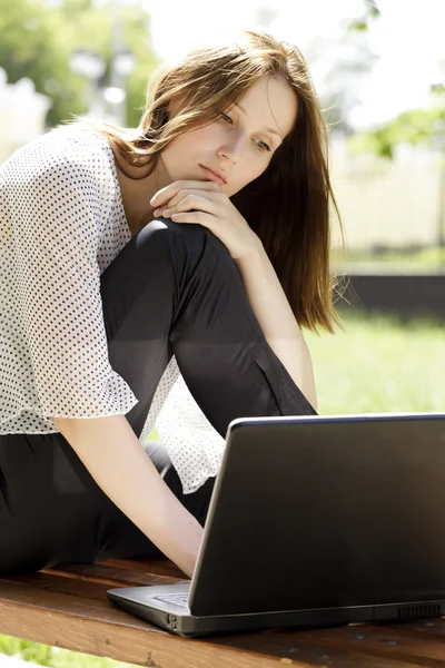 漂亮的年轻女人用一台笔记本电脑在公园 — 图库照片