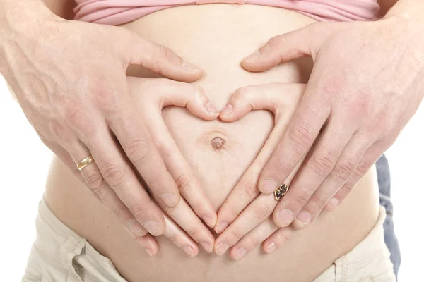Coração em forma de mãos de mulher grávida e seu marido — Fotografia de Stock
