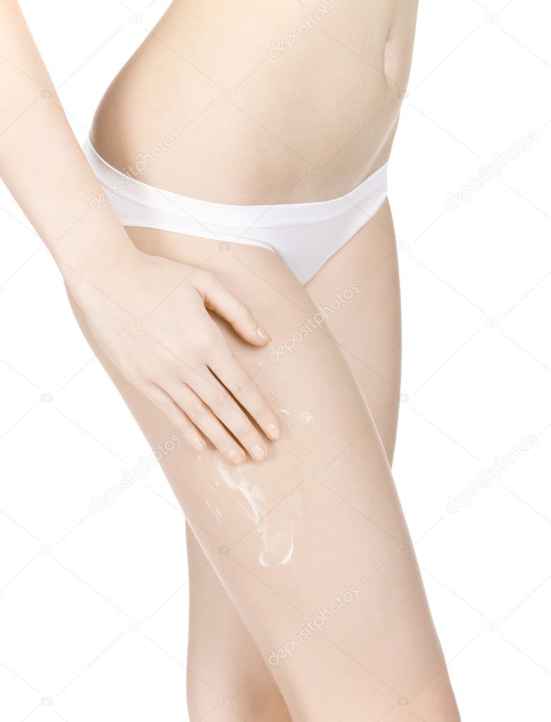 Slim girl spreads cream on her leg