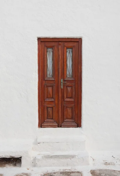 Oud bruin deur met bars op het witte gebouw. — Stockfoto