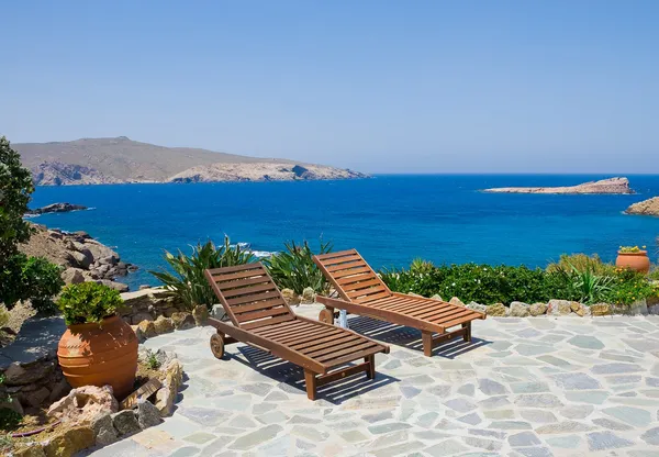 Tuin met ligstoelen op de achtergrond van de zee. Mykonos. Griekenland. — Stockfoto