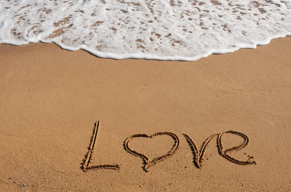 De inscriptie op het zand in de buurt van de zee en de golven - liefde — Stockfoto