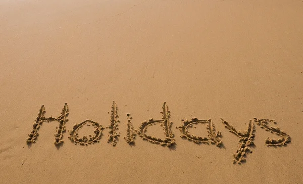 Надпись на песке - праздники, рай для отдыха — стоковое фото
