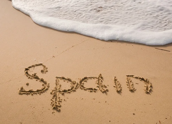 Napis na piasku w pobliżu morza i fale - Hiszpania. — Zdjęcie stockowe