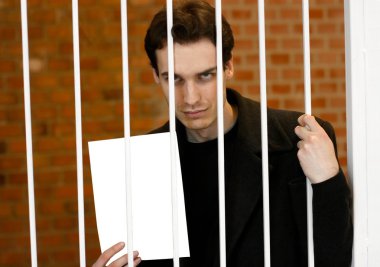 Man locked into a prison cell showing a blank sheet clipart