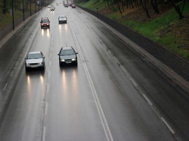 Cars passing by on a wet rainy road clipart