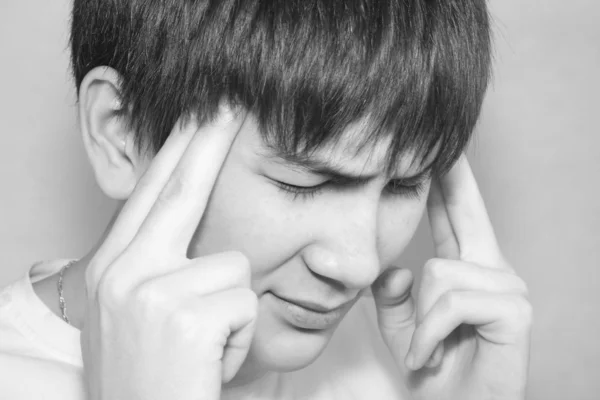 Egy fiatal férfi enyhíti a fájdalmat, a fejfájás, nyomást gyakorolni rá — Stock Fotó