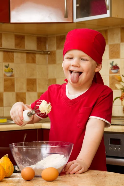 Poika auttaa keittiössä leipoa piirakka, pieni kokki — kuvapankkivalokuva