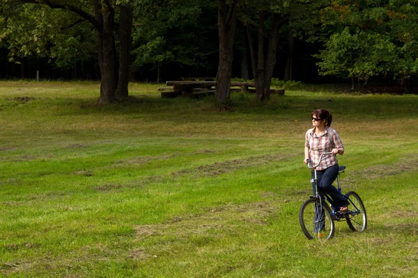 Mladá žena na kole v lese — Stock fotografie