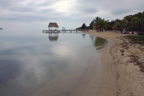 Bech molo a chata na konci, zamračená obloha, čisté moře, palmy tr — Stock fotografie