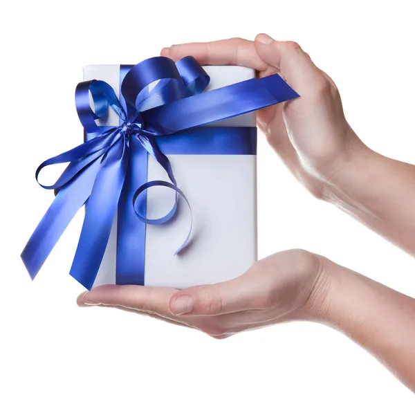 Manos sosteniendo regalo en paquete con cinta azul aislada en blanco Fotos de stock libres de derechos