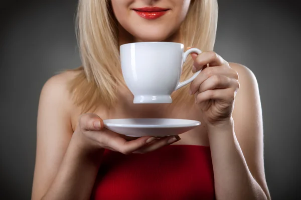 Vrouw in het rood houden cup en de glimlachen — Stockfoto