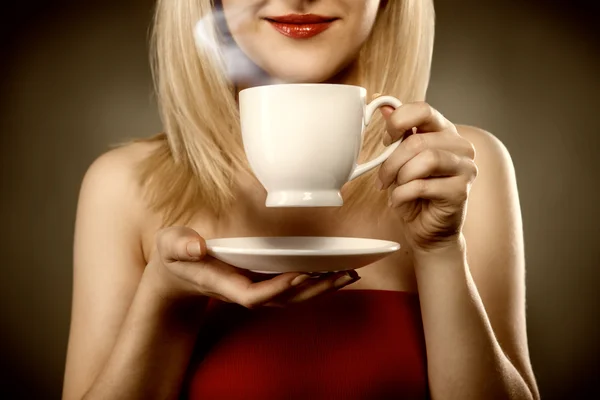 Žena v červeném drží pohár a úsměvy — Stock fotografie