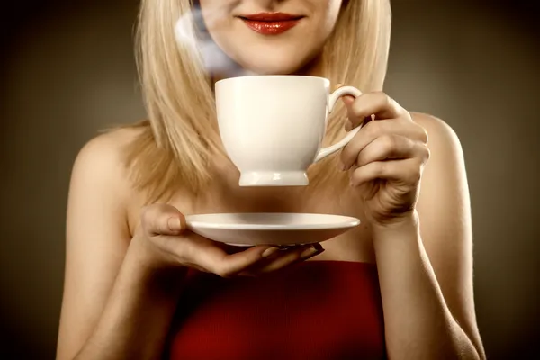Woman in red holding cup and smiles — Stock Photo, Image