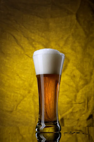 Bier in glas op gele achtergrond — Stockfoto