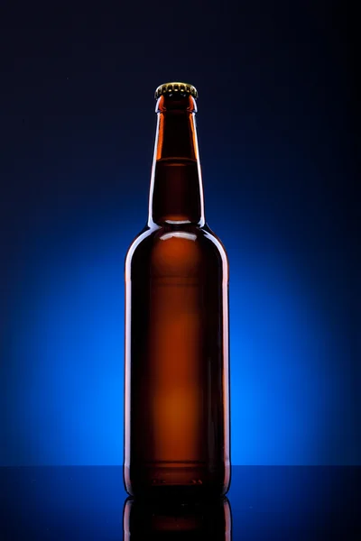 Garrafa de cerveja no fundo azul — Fotografia de Stock
