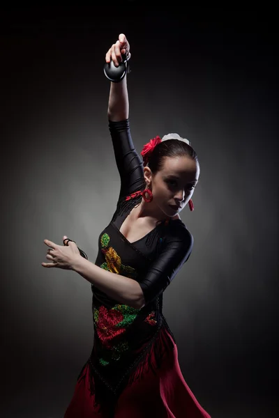 Ung kvinna dansar flamenco med kastanjetter på svart — Stockfoto