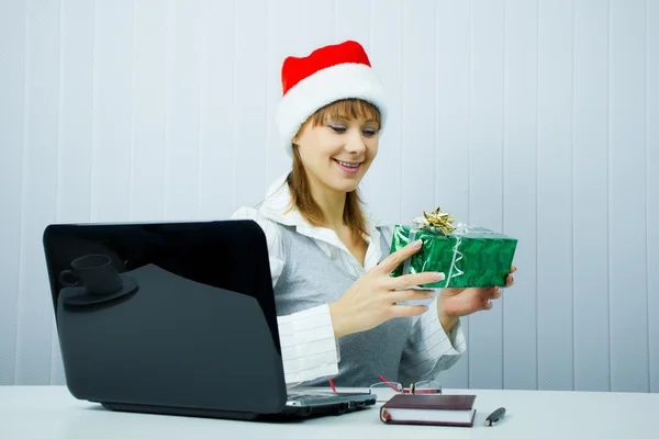 Noel Baba şapkalı bir hediye ile çalışan kız — Stok fotoğraf