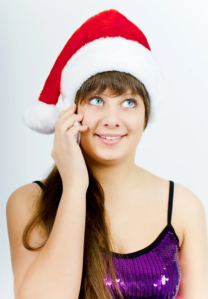 Menina sorridente feliz com chapéu de Papai Noel com um telefone — Fotografia de Stock