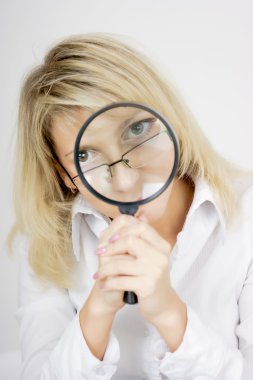 Girl with a magnifying glass on a light background clipart