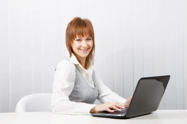 有吸引力的微笑快乐女孩用在办公室的一台笔记本电脑 — 图库照片