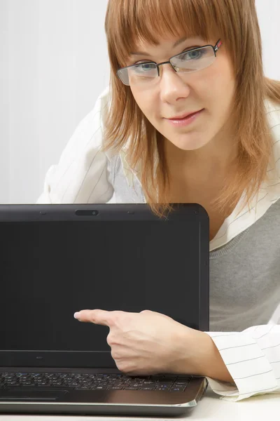 戴着眼镜的女孩在便携式计算机显示器上显示一个手指 — 图库照片