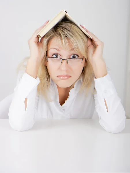 Menina de óculos escondidos sob um livro — Fotografia de Stock